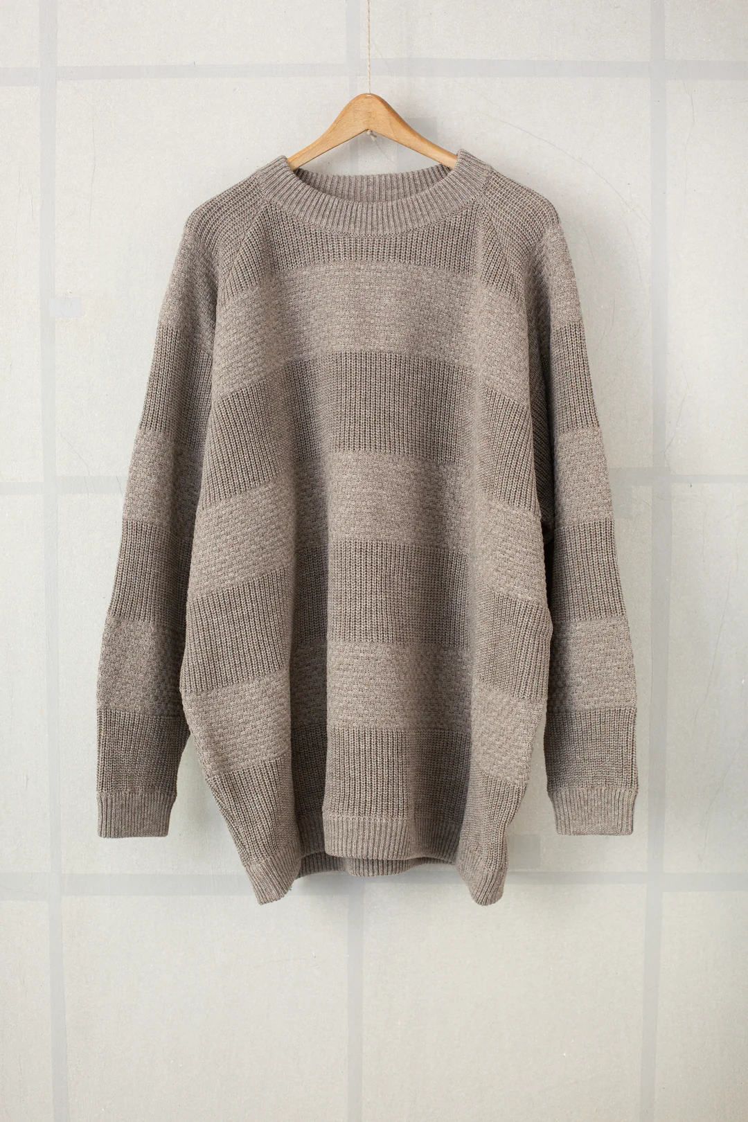 Light grey Sartuul wool sweater with tonal stripes, knitted at a low gauge, on a hanger